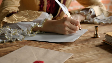 Antique young woman in renaissance dress sitting at table and writing letter with vintage quill pen...