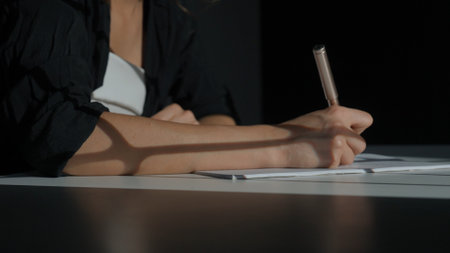 Business woman sitting at office desk writing taking notes in notebook with pen, concentrated person writing down ideas and planning events, close up shot.の写真素材