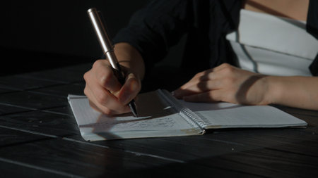 Business woman sitting at office desk writing taking notes in notebook with pen, concentrated person...