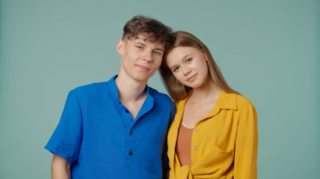 Positive couple of young boyfriend and girlfriend in yellow blue clothes isolated on green...