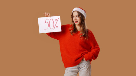Young girl in red sweater and New Years hat poses in studio on beige background