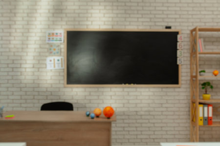Empty elementary school astronomy classroom with chalkboard, workspace for teaching and studying. Teachers desk with planet models, blurred shot.の写真素材