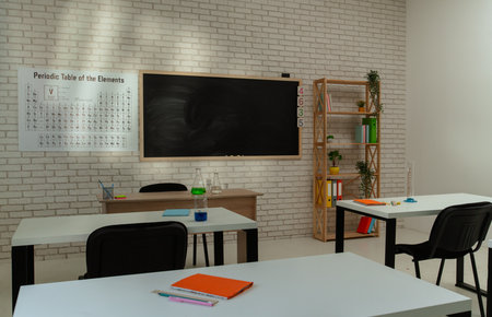 Empty school chemistry classroom with desks, chairs and chalkboard, workspace for studying. notebooks and bottles on tables, periodic table on the wall.の写真素材