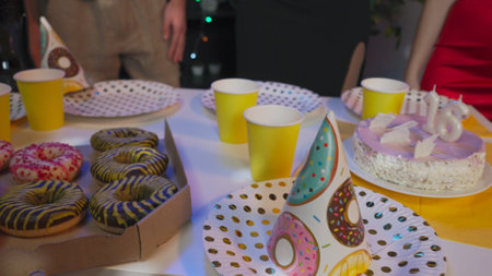 Teenagers birthday party, close up shot of snacks table with donuts, pizzas, drinks and festive cake. Happy group of young people having fun together.の写真素材