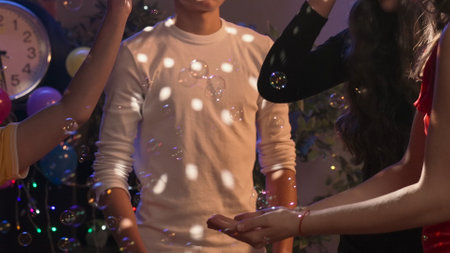 Teenagers birthday party, close up shot of girls and boys dancing at the party, smiling enjoy music and soap bubbles. Happy group of young people having fun together. Slow motion.の写真素材
