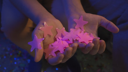 Teenagers birthday party, close up shot of girls and boys holding in hands many pink colorful star...