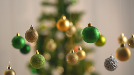 Christmas tree golden, silver and green balls, sparkling colorful toys hanging from above, sparkling ornaments garland close up shot on blurred festive background.の写真素材