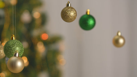 Christmas tree golden, silver and green balls, sparkling colorful toys hanging from top, glittering ornaments garland close shot on blurred festive background.の写真素材