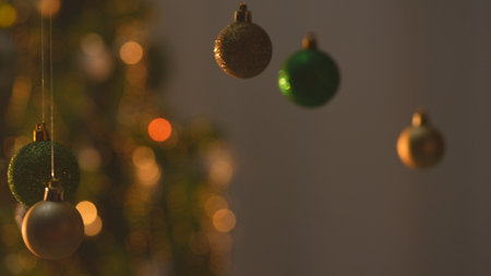 Christmas tree golden green silver balls, sparkling toys hanging from above, glittering ornaments garland close shot on blurred festive background.の写真素材