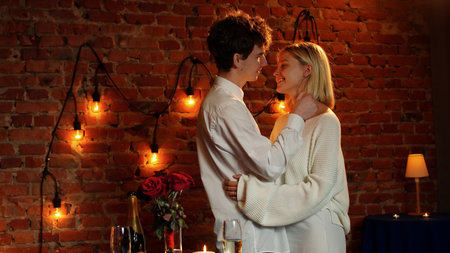 Couple celebrating valentines day and having a romantic dinner in restaurant, man and woman dancing holding hands and smiling, close up.の写真素材