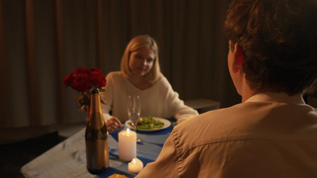 Couple celebrating valentines day and having a romantic dinner in restaurant, sitting at table and enjoying meal, man and woman talking and smiling, close view.の写真素材