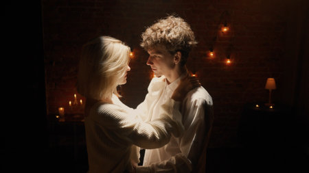 Couple celebrating valentines day and having a romantic dinner in restaurant, man and woman dancing and smiling in darkness under spotlight, close up.の写真素材