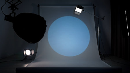 Professional studio for photo and video production filming with modern lighting equipment, large white cyclorama background, blue spotlight setup.の写真素材