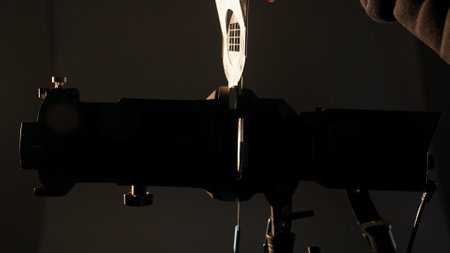 Professional studio for photo and video production filming with modern lighting equipment, close up of details, assistant puts window pattern filter in spotlight.の写真素材