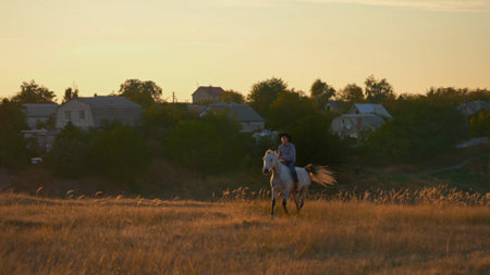 Man in cowboy costume riding horse against sunset.の写真素材