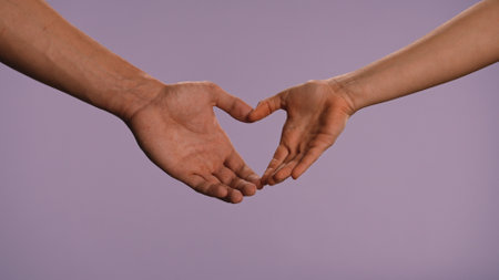 Man and woman hands showing gestures, making heart love hand sign, isolated on purple studio background, close up shot. Valentines day advertising concept.の写真素材