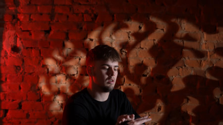A figure in black clothes dancing against a red brick wall