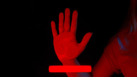 A hand touches glass screen panel, open palm print on transparent surface, red light scanner...