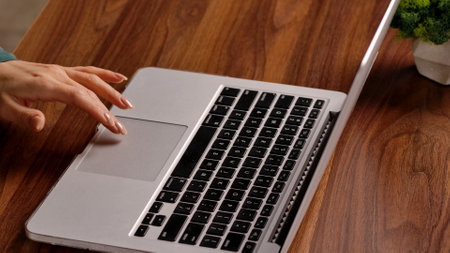 Young business woman sitting at desk working late in office loft, using laptop, close up shop of...