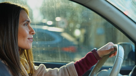 Young brunette woman in the morning in the car riding to work, close up shot woman in auto driving a car to office, looking in the window, positive expression.の写真素材