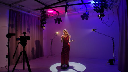 Studio for photo video production filming with lighting equipment and cyclorama, woman singer in red...