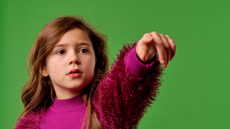 Girl child with shocked face pointing with hand at side and covering face with hands, scared expression, isolated on chroma key green screen studio background mockup.の写真素材