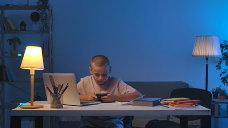 A schoolboy sits at a table in a room doing homework.
