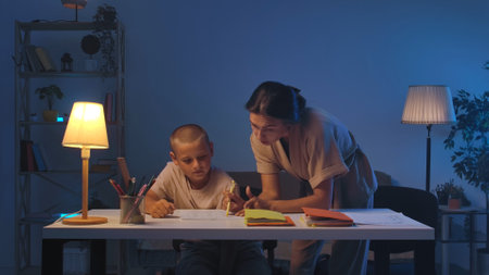 A schoolboy sits at a table in a room doing homework.の写真素材