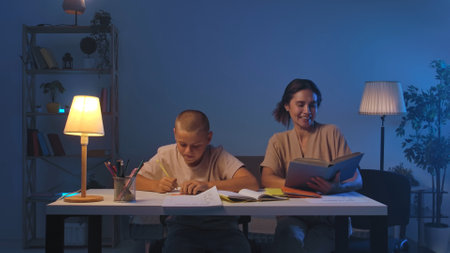 A schoolboy sits at a table in a room doing homework.の写真素材