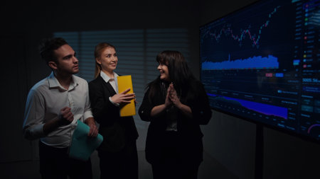 Woman chief executive leads meeting with colleagues in boardroom, analyzing financial data infographics on big display and reporting on company success.の写真素材