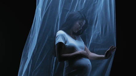 Artistic shot of a young Asian pregnant woman using a transparent fabricの写真素材