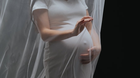 Artistic shot of a young pregnant woman using a transparent fabricの写真素材