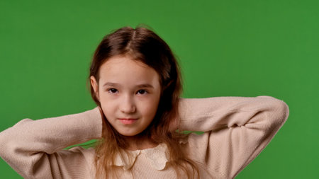 Little girl child posing at camera, positive expression, isolated on chroma key green screen studio background mockup.の写真素材