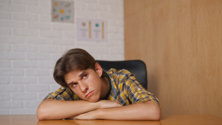 Man college student studying at home pov, sitting at desk, listening watching lesson online on computer, bored sleepy and tired expression. Modern online education.の写真素材