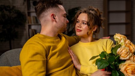 Happy couple celebrating valentines day together at home, man and woman sitting on the sofa and...