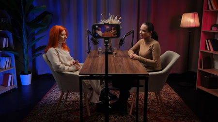 Two Influencers of women being interviewed in a loft-style podcast studioの写真素材