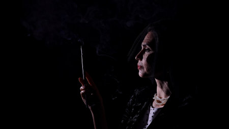 Woman actress silhouette in retro outfit with pin-up hairstyle and makeup posing at camera isolated on black background.の写真素材