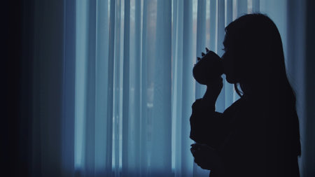 Silhouette of Woman Drinking Hot Beverage by the Windowの写真素材