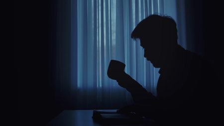 Silhouette of Person Drinking Coffee in Dimly Lit Roomの写真素材