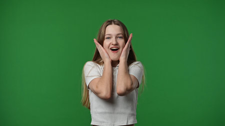 Teenage girl posing at camera screaming in excitement and surprise, smiling positive expression,...