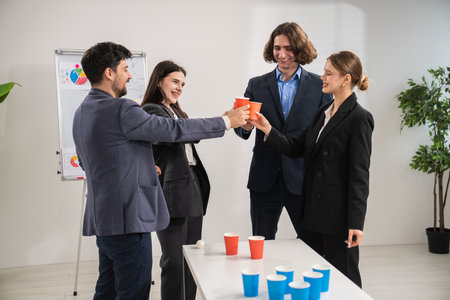 Team Celebrating Successful Office Event with Drinks and Joyful Atmosphereの写真素材