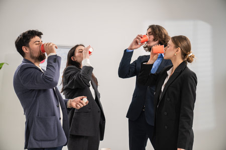 Team Celebrating Successful Office Event with Drinks and Joyful Atmosphereの写真素材