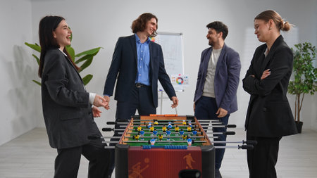 Colleagues Enjoying a Friendly Foosball Match in Office Setting