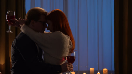 Couple Embracing by Candlelight with Glasses of Wine