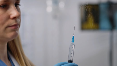 Focused Nurse With Syringe Ready for Medical Procedureの写真素材