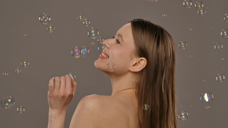 Woman Enjoying Colorful Bubbles Floating Around Her Joyfullyの写真素材