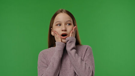 Teenage girl posing at camera holding hands, wow surprise, smiling positive expression, isolated on chroma key green screen studio background mockup.の写真素材