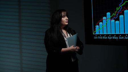 Woman chief executive standing in boardroom, looking analyzing financial data infographics on big...