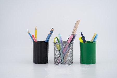 Assorted Stationery Items in Colorful Holders on White Background