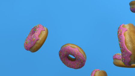 Floating Pink Frosted Donuts with Sprinkles on Blue Backgroundの写真素材